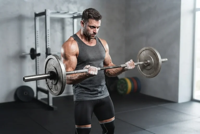 Atleta ejecutando curl de bíceps con barra para aplicar tensión mecánica y generar hipertrofia muscular real.